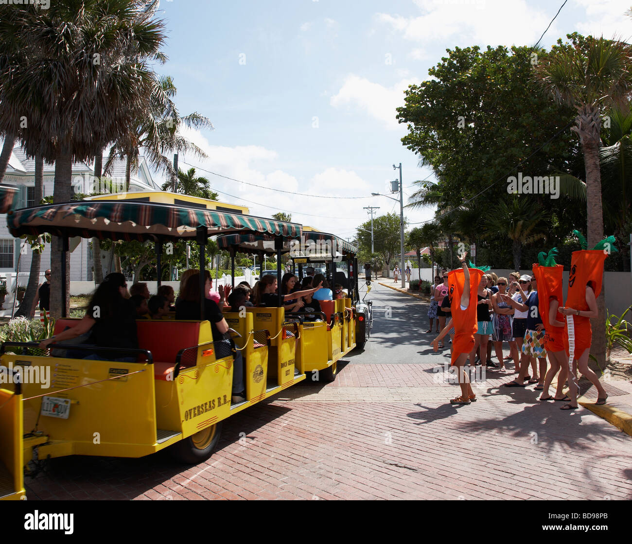 Un mini treno porta i turisti passato alcune persone vestite come le carote Foto Stock