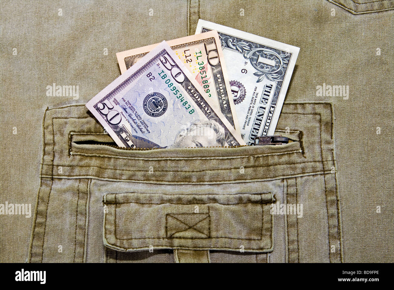 Tre differenti valute US dollar note nella tasca di un paio di pantaloni khaki Foto Stock