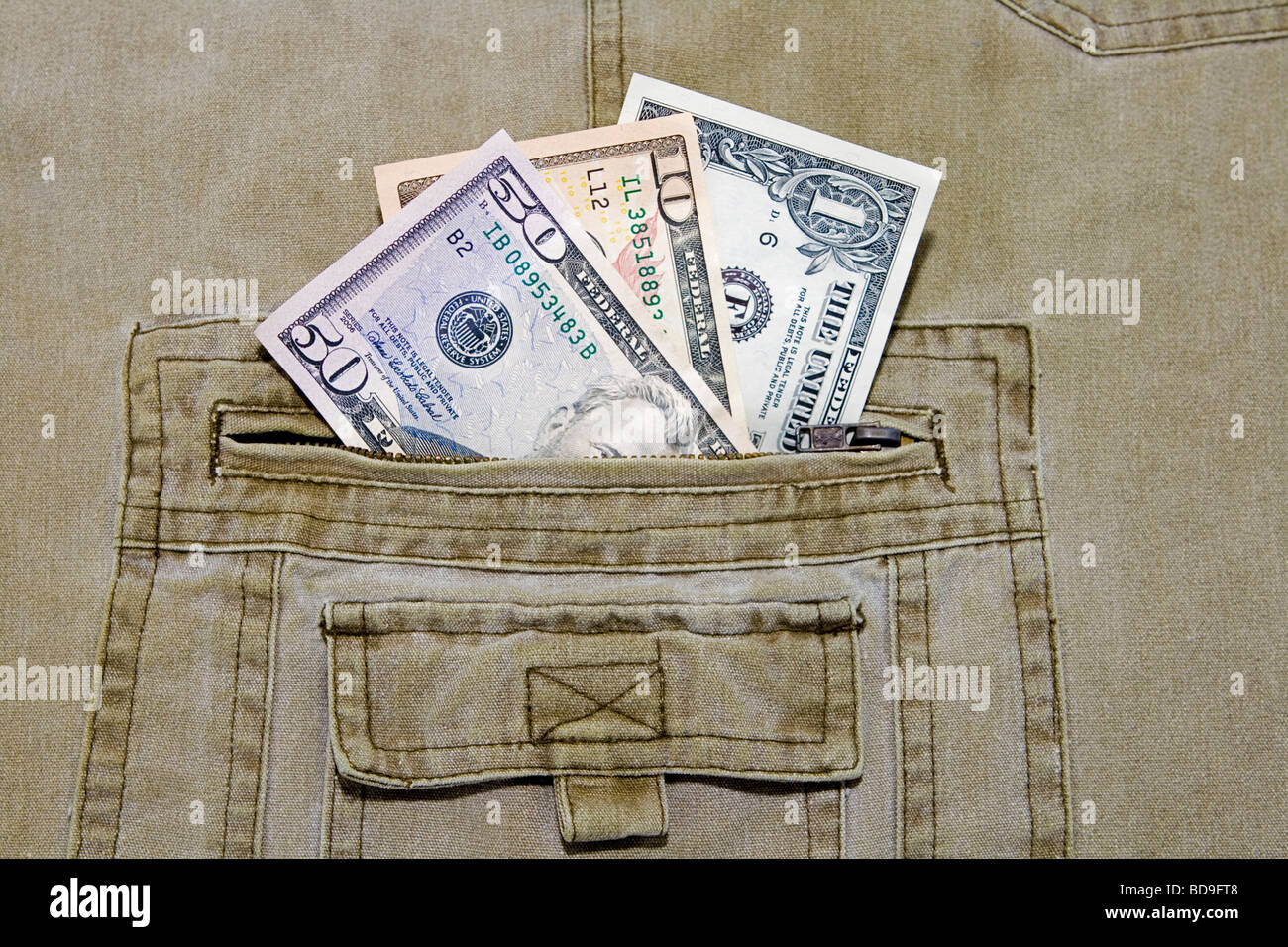 Tre differenti valute US dollar note nella tasca di un paio di pantaloni khaki Foto Stock