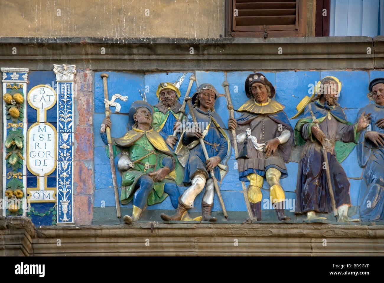 Smalto rilievo della piastrella che mostra i pellegrini sulla Via Francigena, sulla facciata dello Spedale del Ceppo di Pistoia Foto Stock