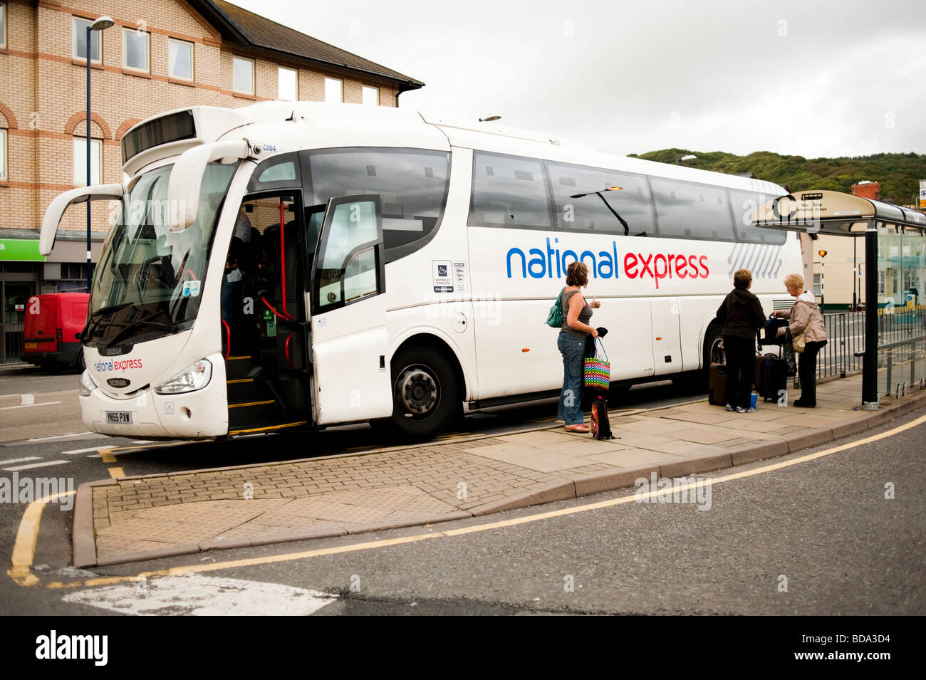 I passeggeri che emergono da un National Express a lunga distanza autobus ad una fermata del bus Foto Stock