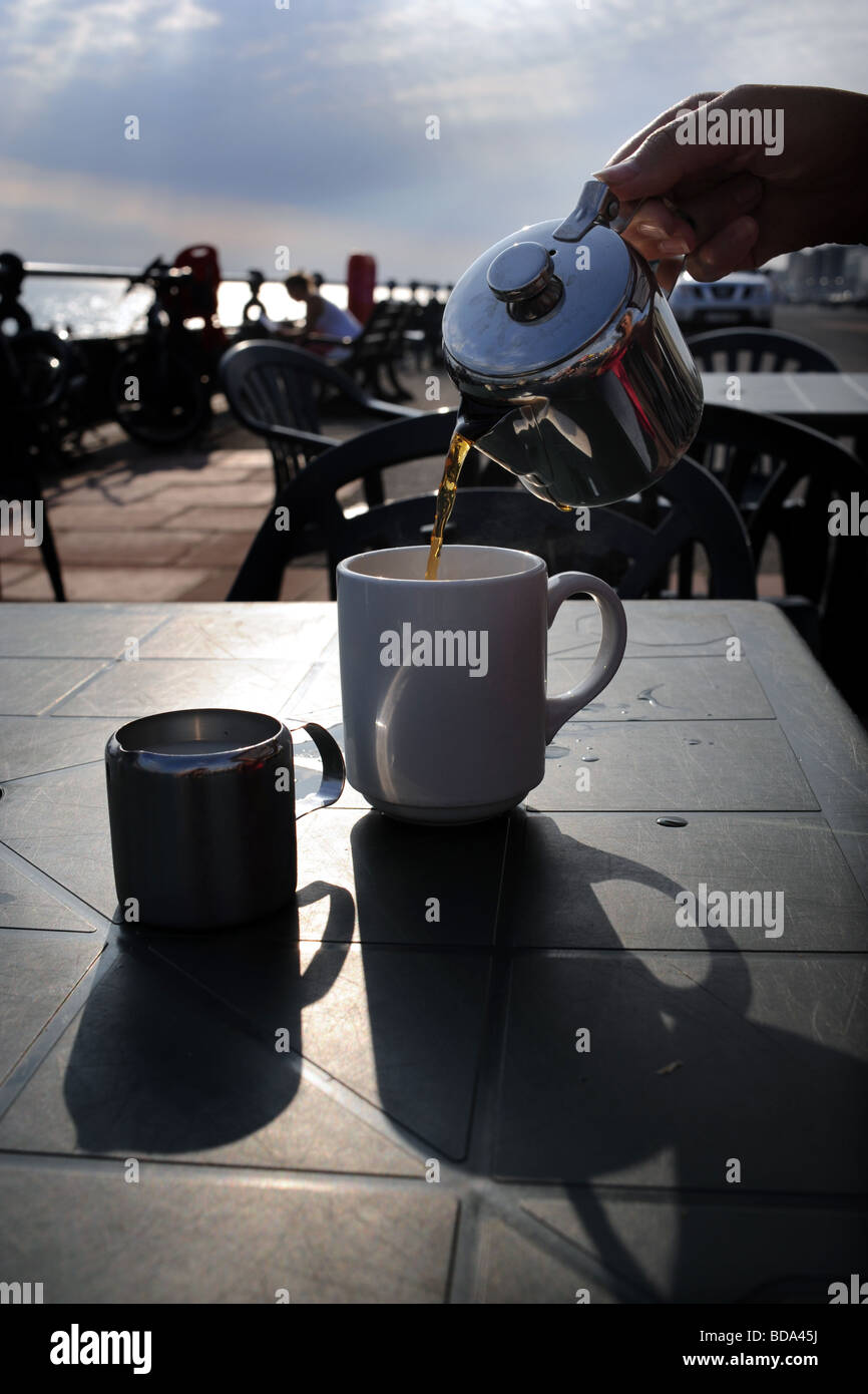 Versando una tazza di tè da teiera in un caffè sul mare a Brighton Foto Stock