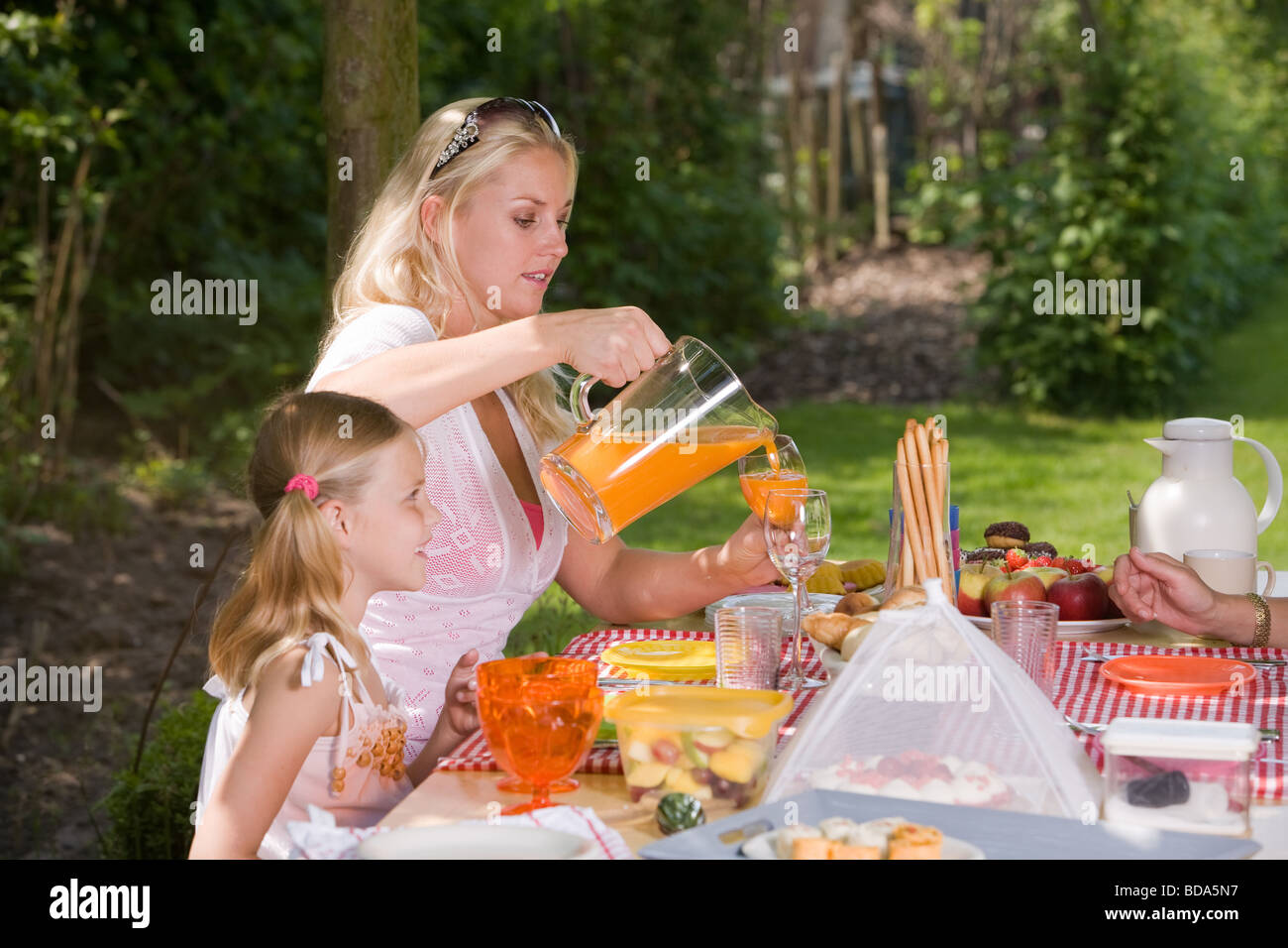Famiglia seduti all'aperto in un giorno di estate godendo un picknick Foto Stock