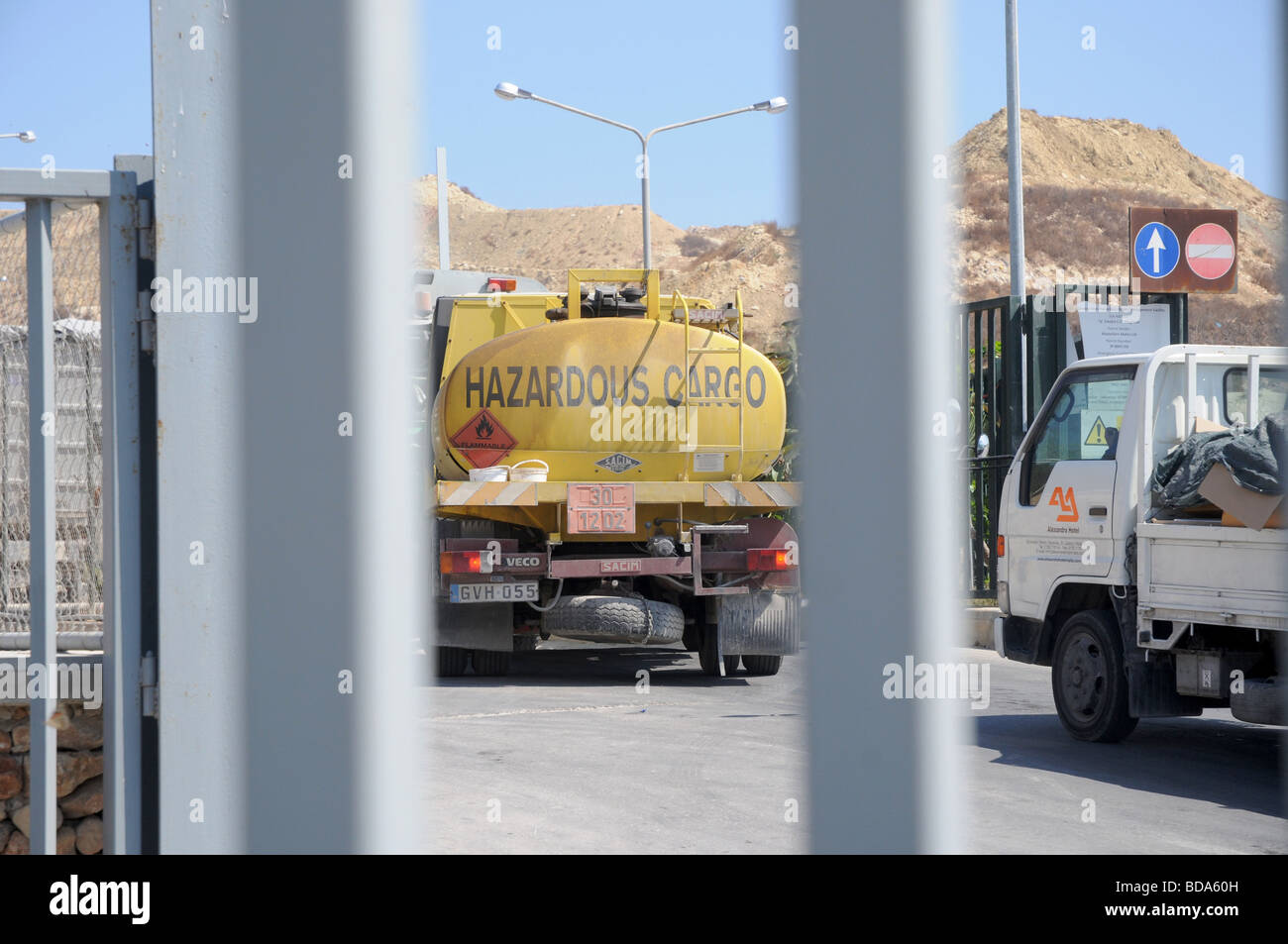 Giallo camion che trasportano carichi pericolosi passando attraverso un ingresso di discarica. Foto Stock