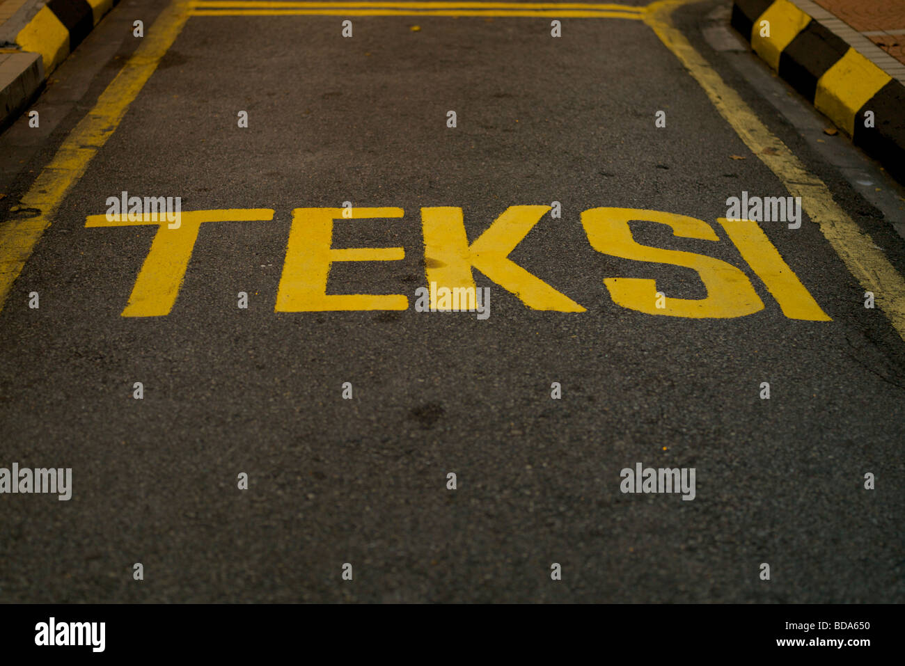 Teksi segno taxi sulla strada in giallo la scrittura in Malese. Foto Stock