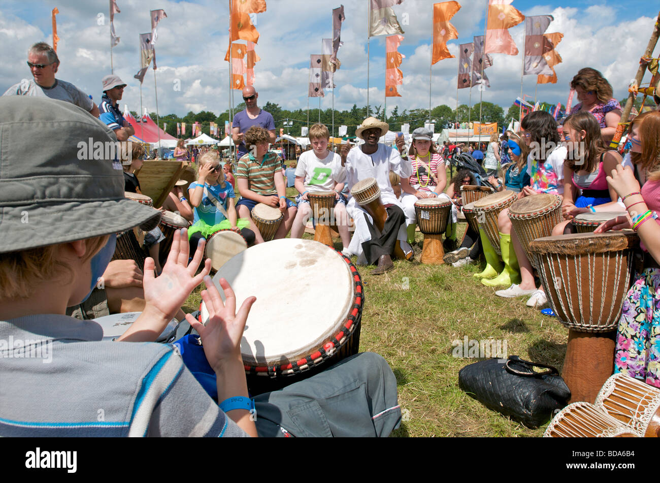 Famiglie e bambini godendo di un drumming workshop al Womad Festival di musica con bandiere e la folla Foto Stock