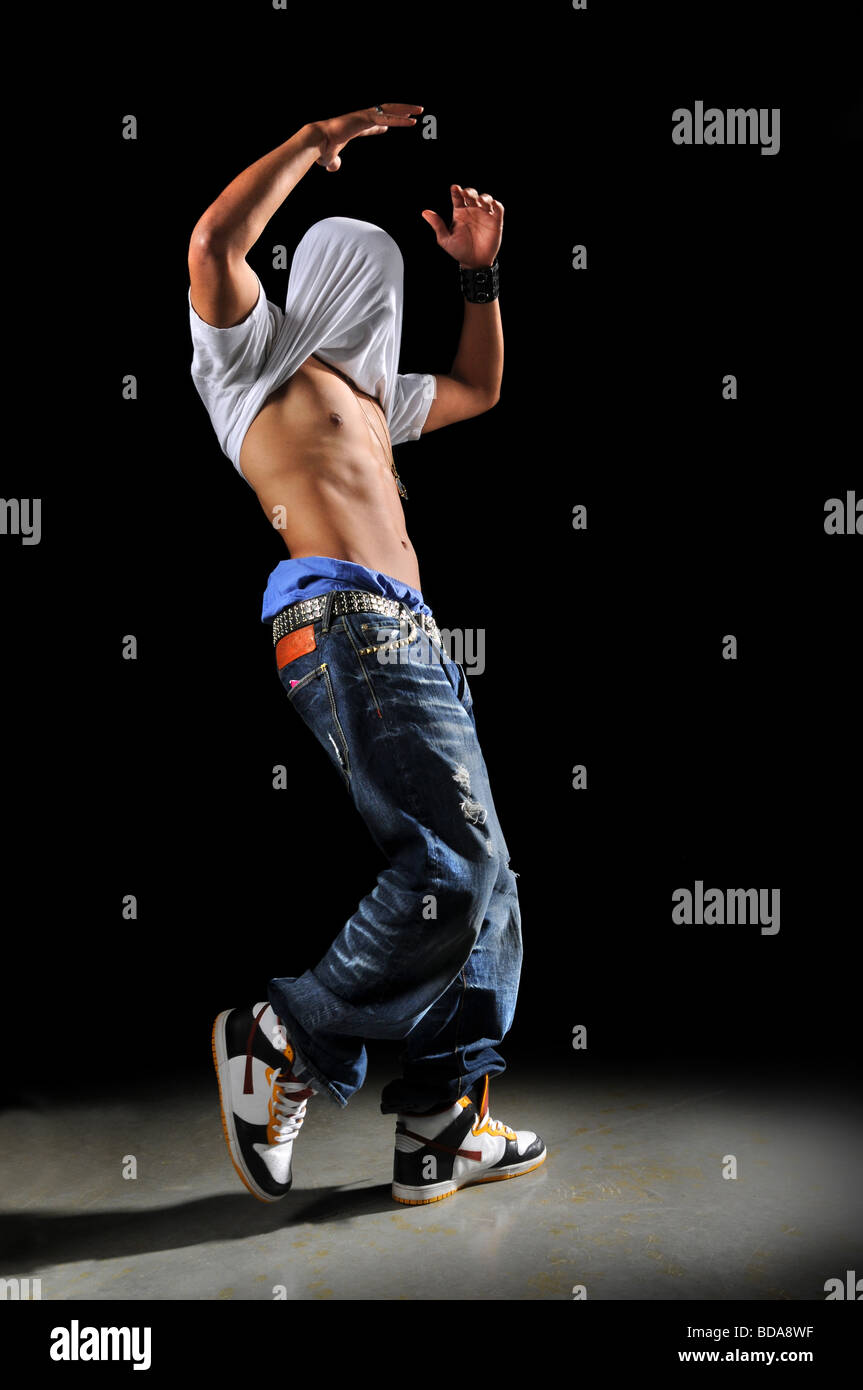 Hip hop Danzatrice con il capo coperto da t shirt su uno sfondo nero Foto Stock