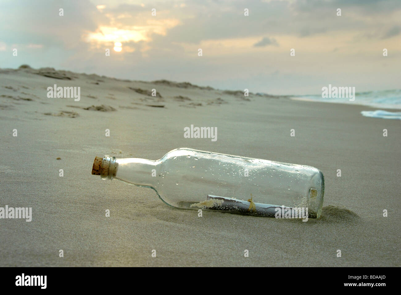 Un messaggio in bottiglia lavato a terra durante un tramonto Foto Stock