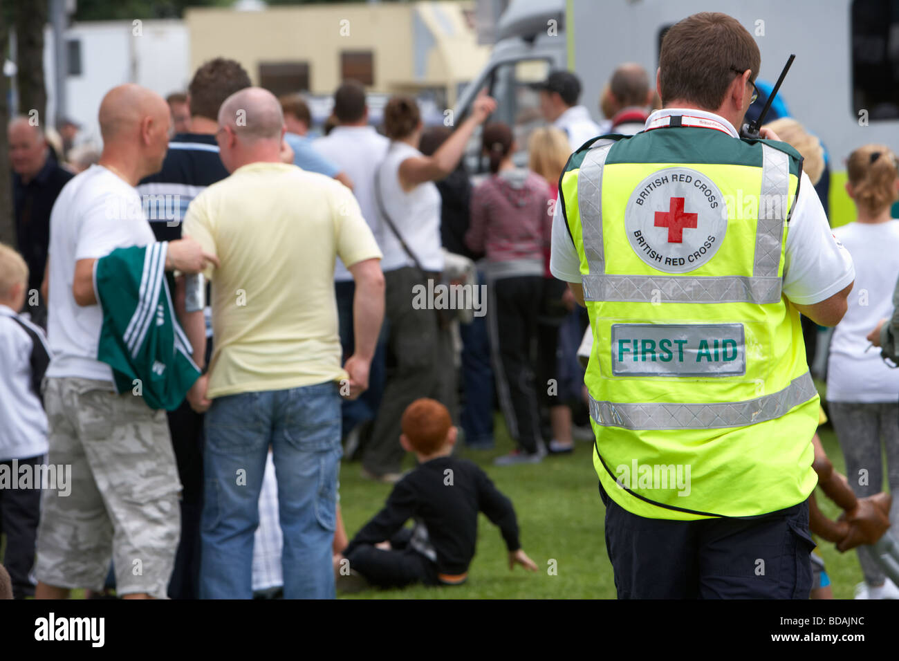 Membro della Croce Rossa britannica prima squadra di aiuto sulla radio a piedi attraverso una folla in corrispondenza di un evento esterno a Belfast Foto Stock