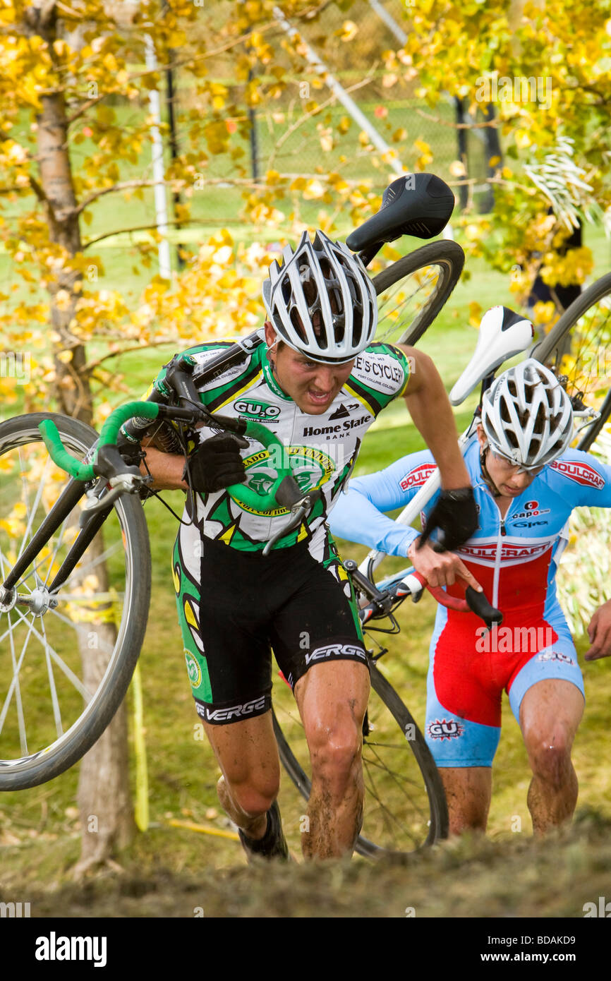 Cyclecross racer in esecuzione fino alla cima di una collina con la sua bicicletta sulla sua spalla Foto Stock