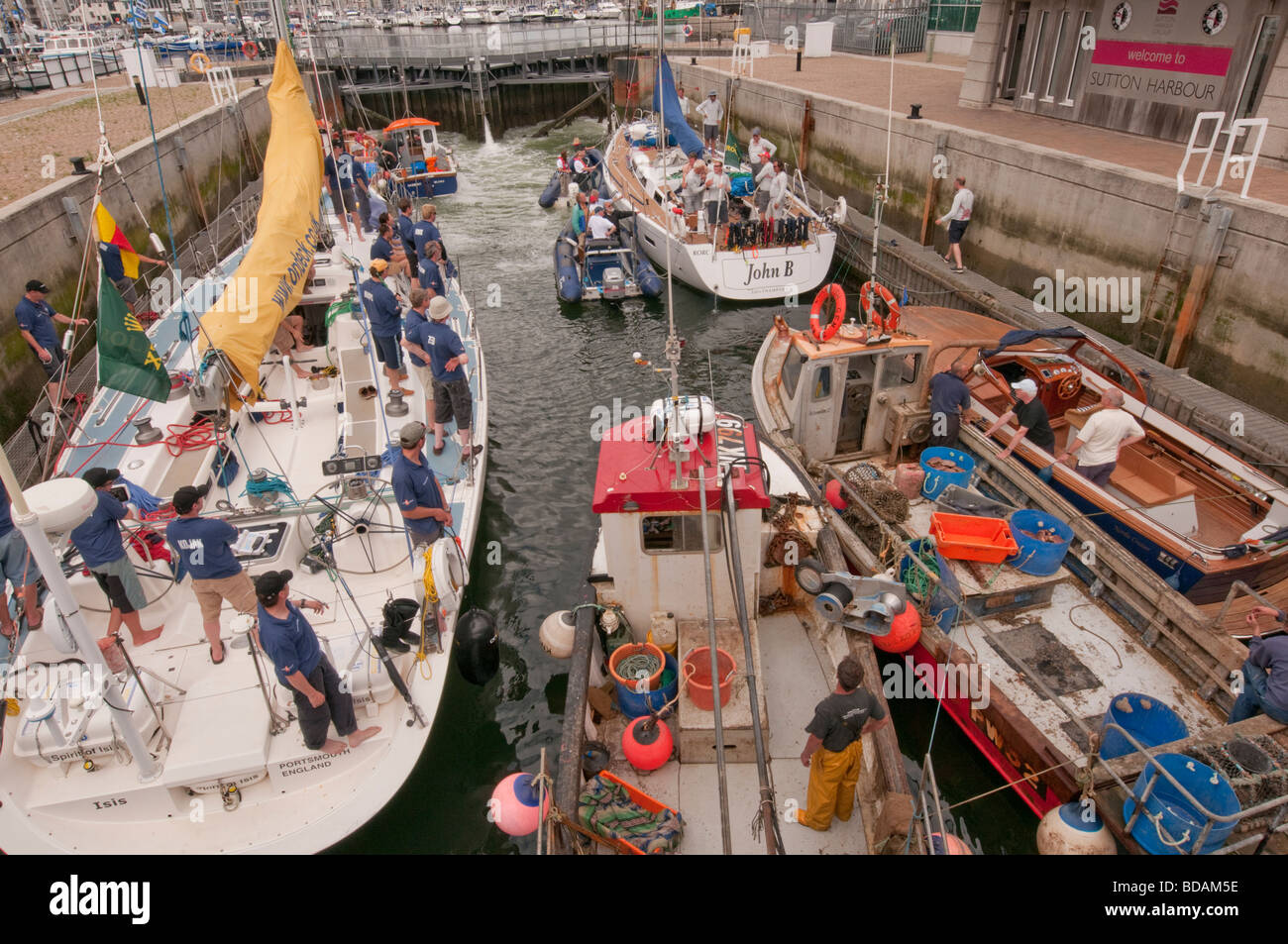 Yacht da Rolex Fastnet race 2009 attendere lungo il lato di barche da pesca nella serratura per immettere Sutton Harbour. Foto Stock