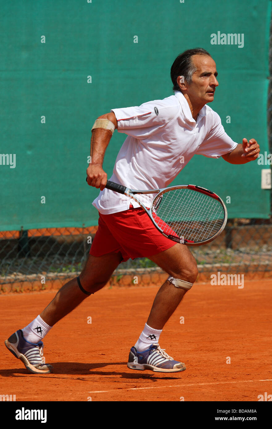 Uomo anziano a giocare a un torneo di tennis Foto Stock