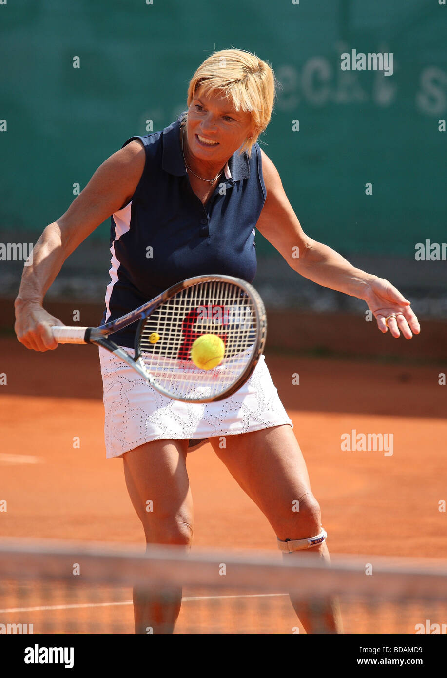 Donna Middleaged Giocare il rovescio volley in un torneo di tennis Foto Stock