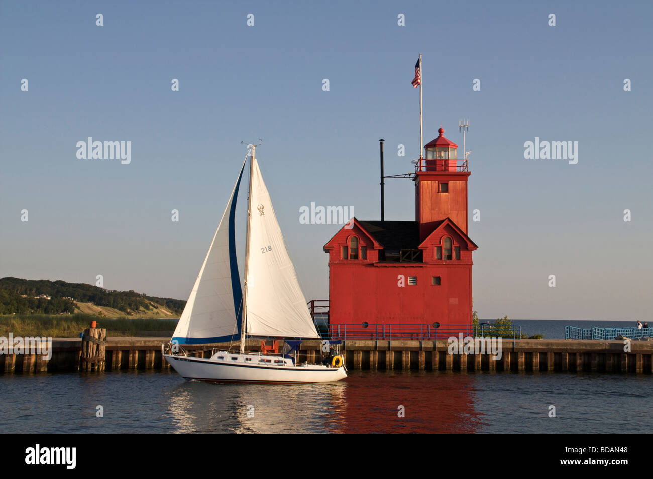 Barca a vela entrando in porto canale stato di Holland Park Michigan passando Big Red la voce faro Foto Stock