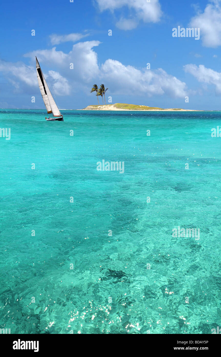 Barca a vela vela su acque cristalline con isola in background Foto Stock