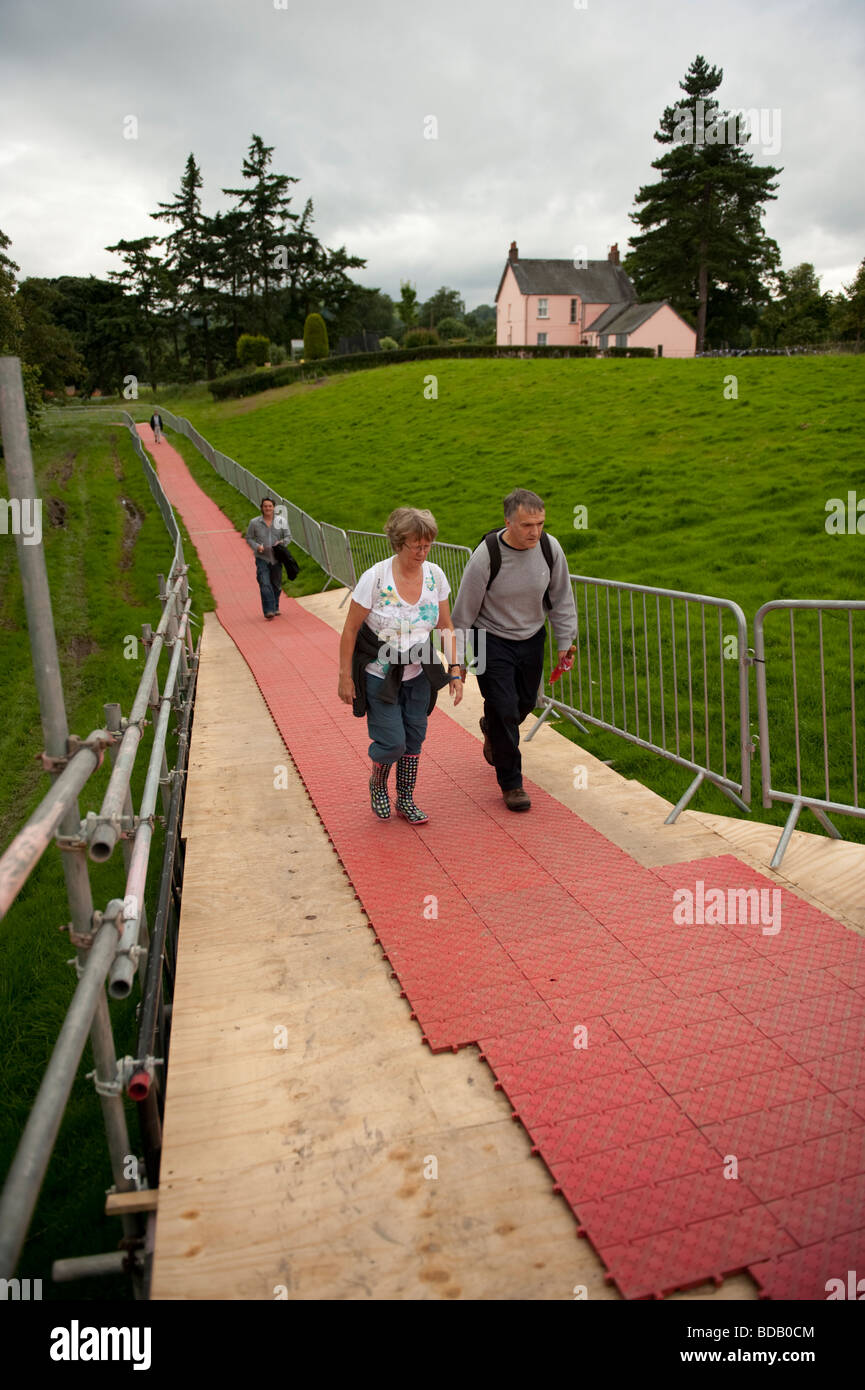 La gente camminare lungo rosso in plastica di binari posati su erba verso l'Eisteddfod nazionale del Galles Bala Agosto 2009 Foto Stock