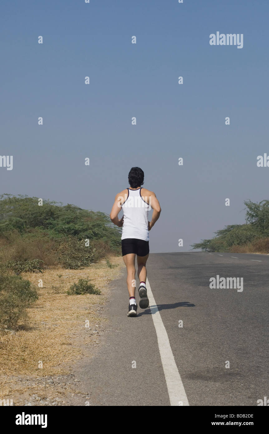 Vista posteriore di un uomo jogging su strada Foto Stock