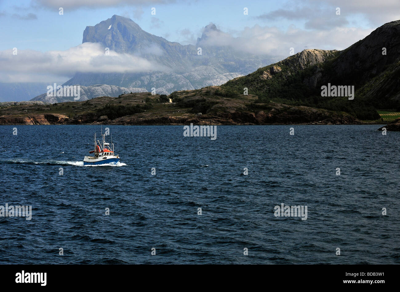 Nave da pesca con le montagne sullo sfondo Foto Stock