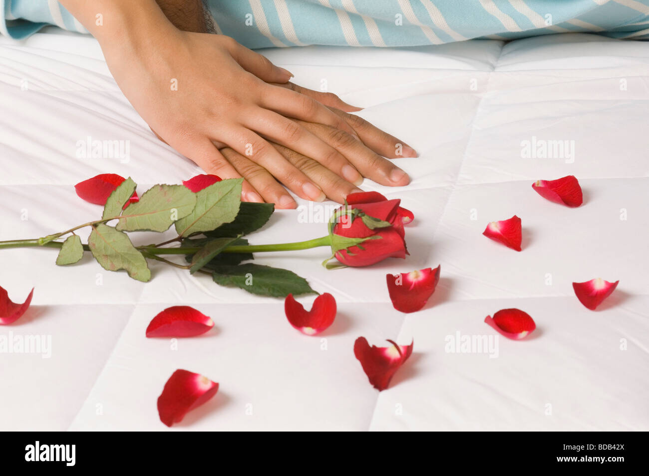 Paio disteso sul letto con petali di rosa Foto Stock