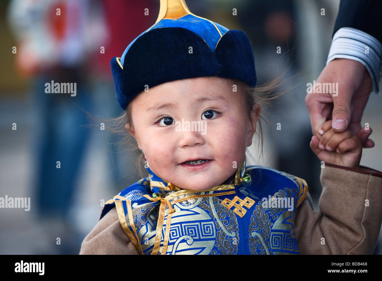 Felice e giovane ragazzo mongola vestito in abiti tradizionali e Hat detiene la mano del padre ad Ulaan Baatar, Mongolia Foto Stock