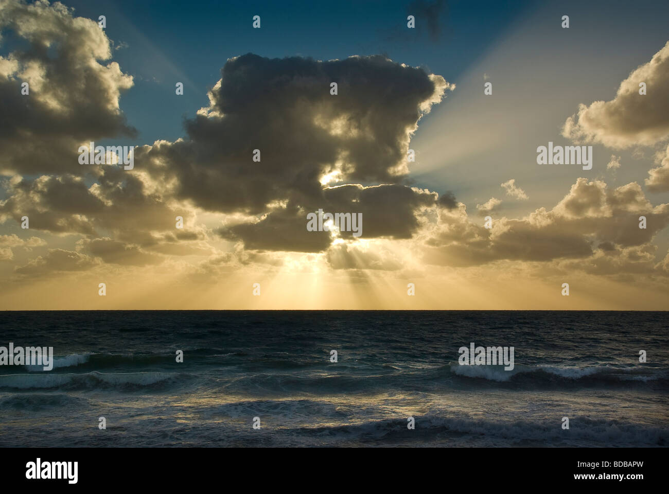 Un tramonto spettacolare sull'oceano con forti raggi di luce e nuvole drammatico Foto Stock