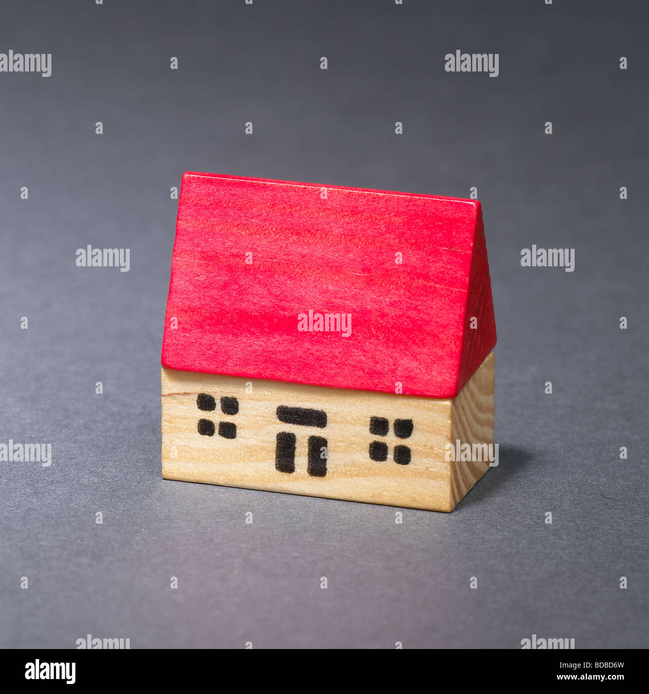 Giocattolo di legno casa con il tetto rosso su sfondo grigio Foto Stock