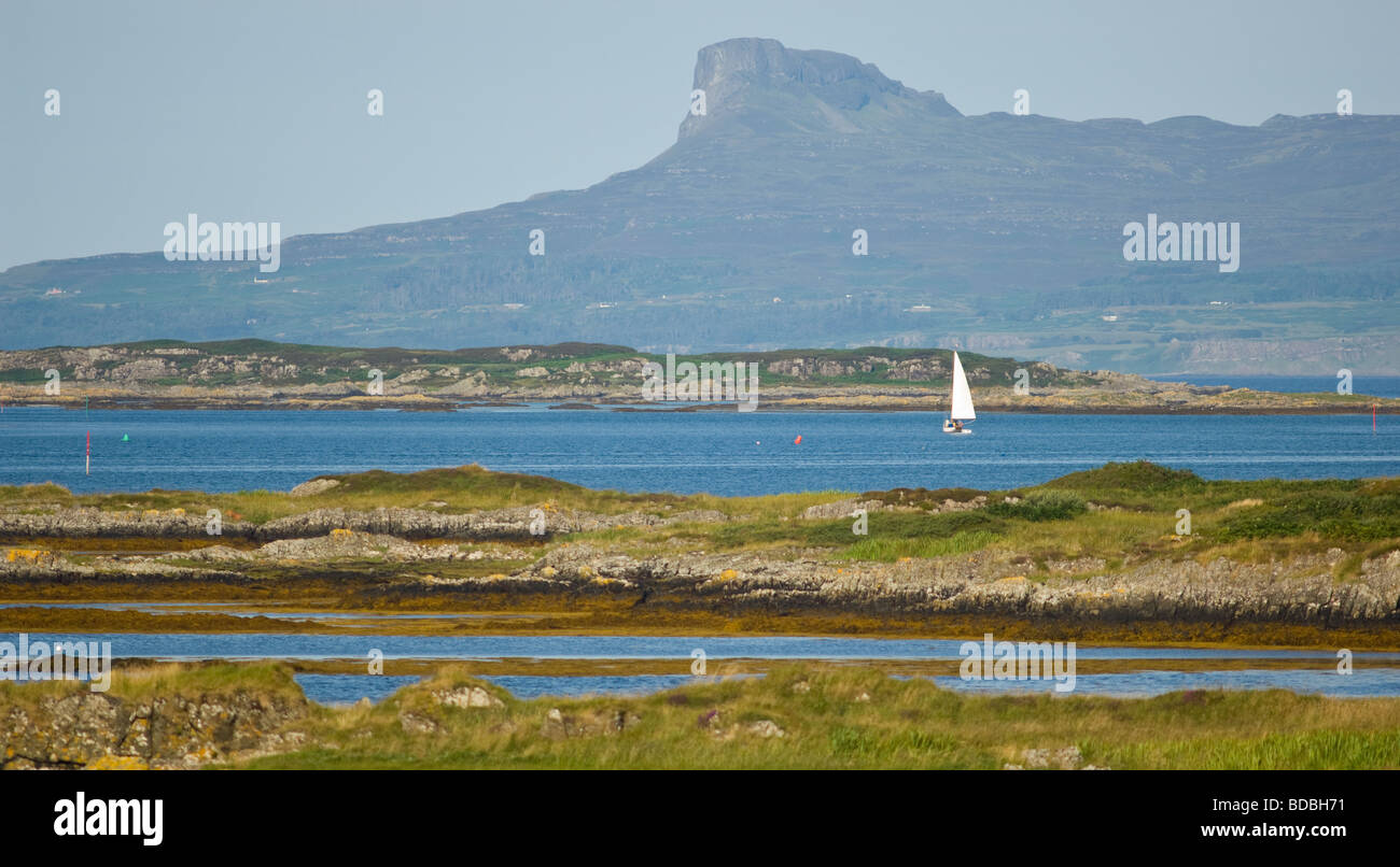 Imbarcazione a vela in mare al largo Arisaig con la nervatura inclinata della lava noto come Sgurr sull'Isola di Eigg. Foto Stock