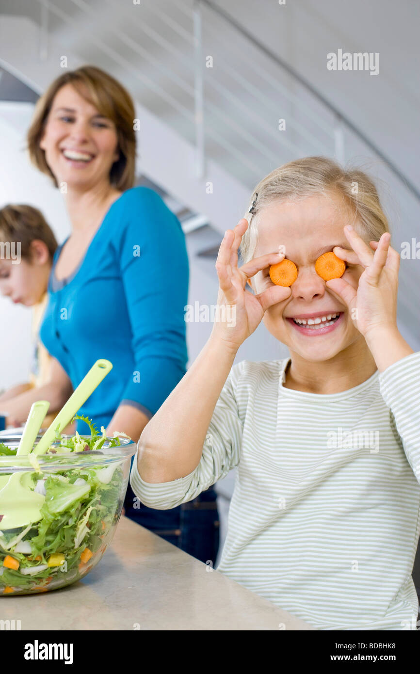 Madre guarda la sua figlia di fare divertire con le fette di carota Foto Stock