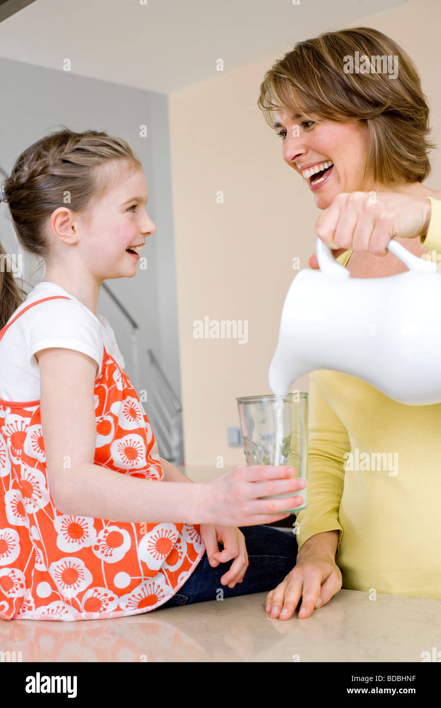 Madre versando il latte nella sua figlia in vetro Foto Stock