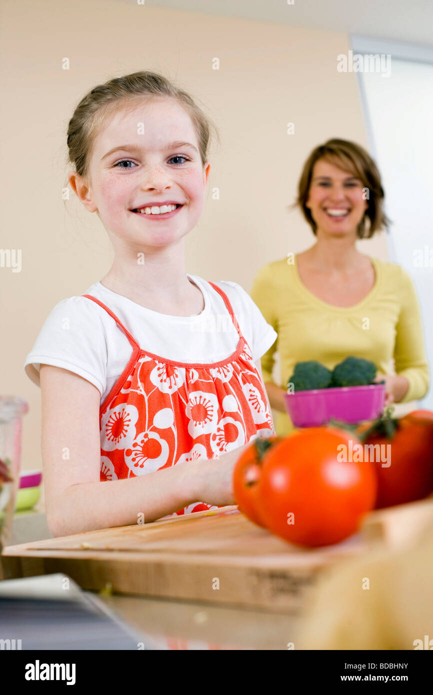 Ritratto di giovane ragazza aiutando la madre in cucina Foto Stock