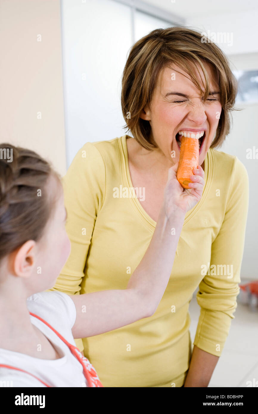 Ragazza giovane alimentazione di sua madre la carota Foto Stock
