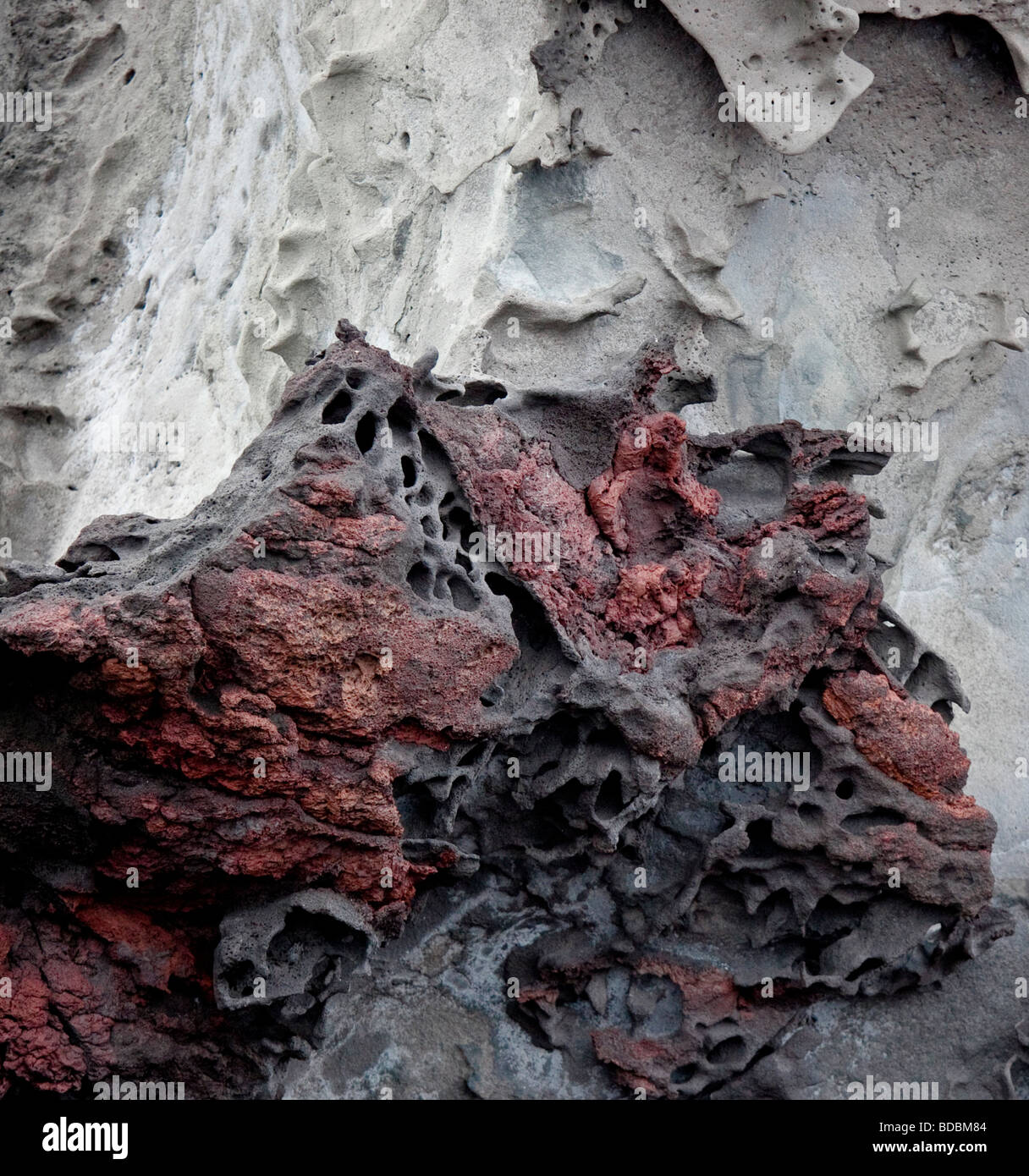 Ricche di ferro e depositi nella roccia vulcanica dare la costa di Bartolome una ricca, colore rosso. Foto Stock