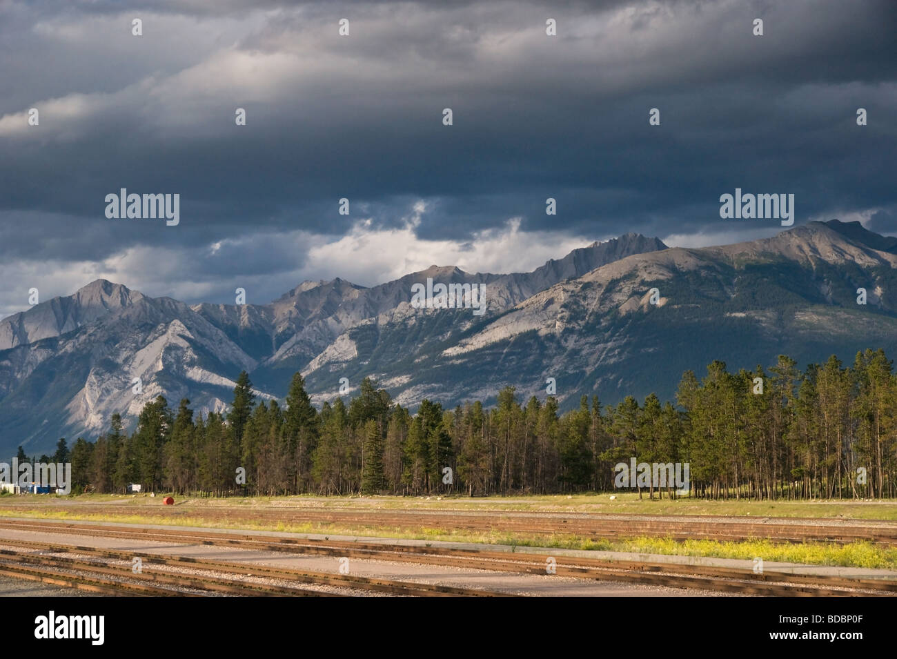 Nuvole raccogliendo oltre le montagne rocciose in Jasper, Alberta - in primo piano un deserta cantiere ferroviario. Foto Stock