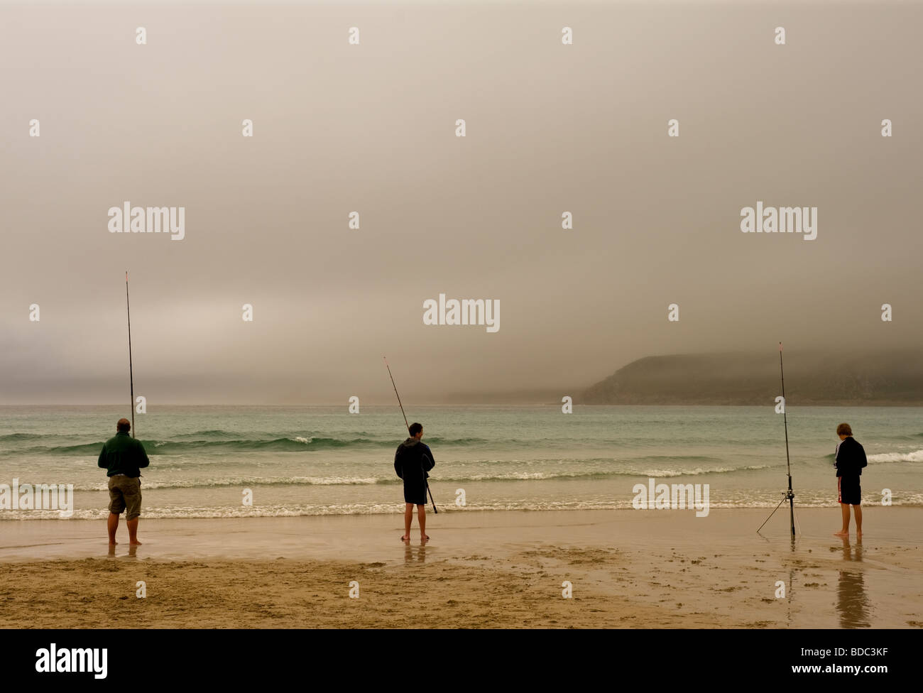 Tre pescatori pesca in spiaggia in una nebbiosa giornata in Sennen in Cornovaglia. Foto Stock