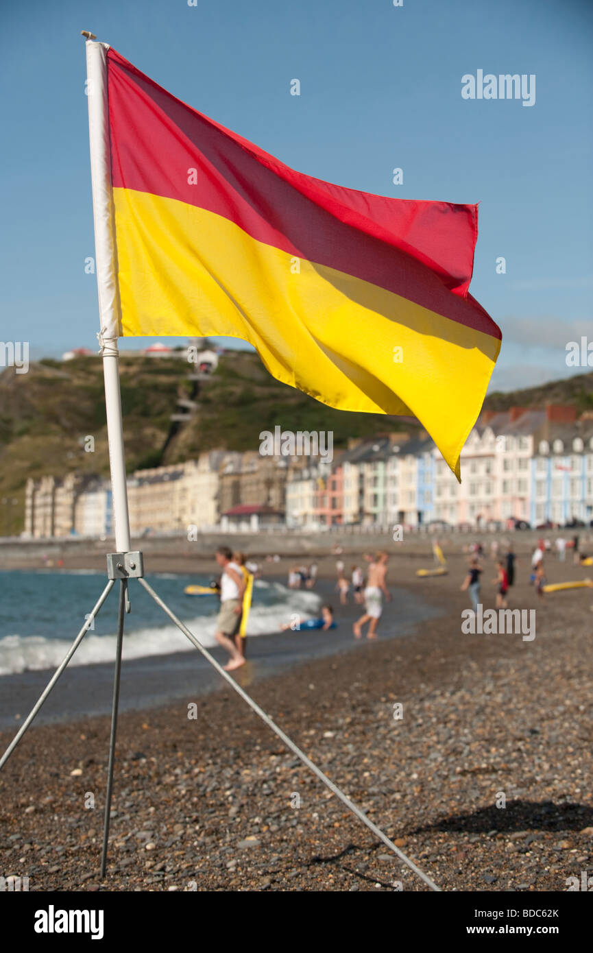 Rosso e Giallo banner di sicurezza a volare su Aberystwyth Beach estate nel pomeriggio il Galles Ceredigion REGNO UNITO Foto Stock