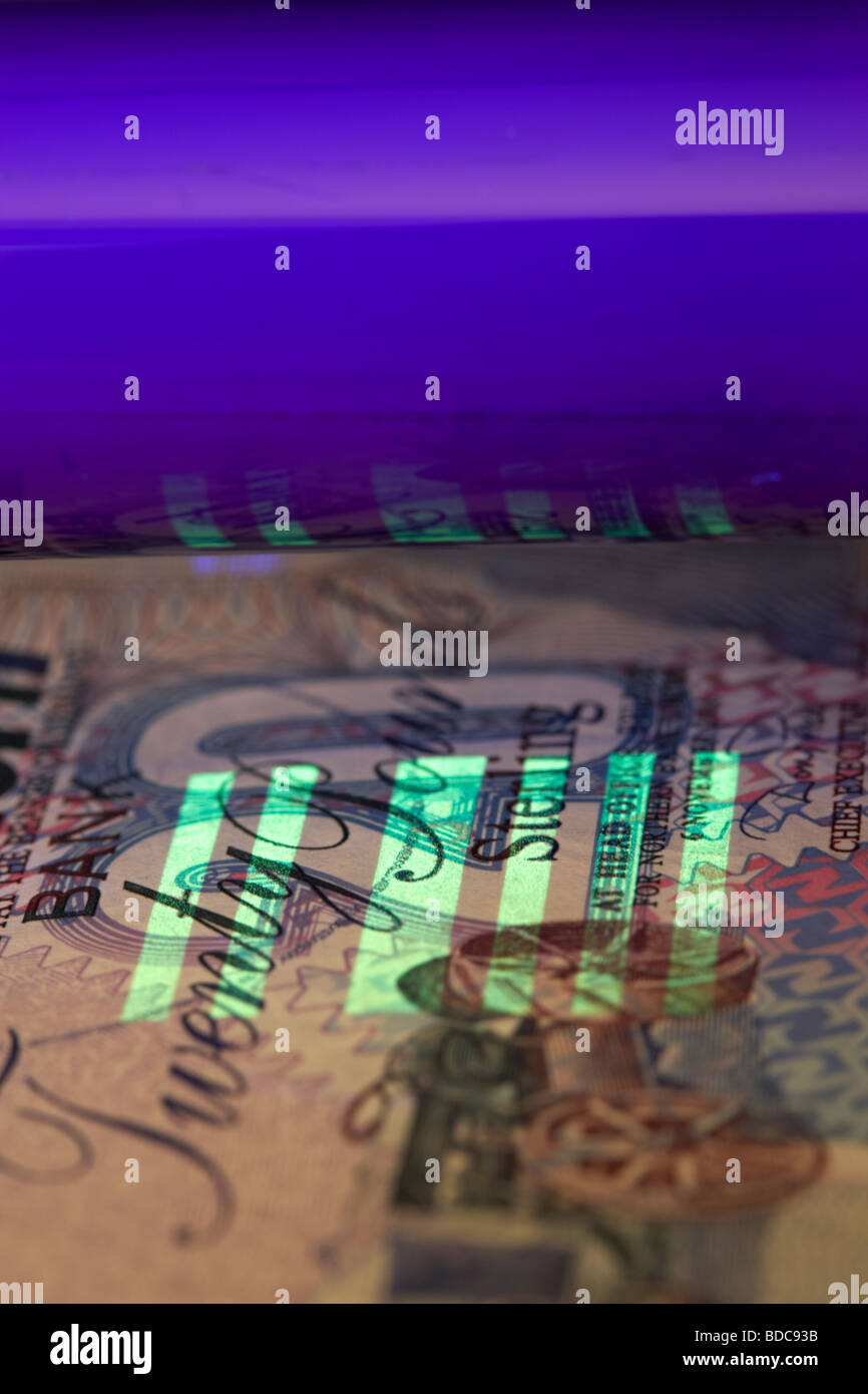 Utilizzando un ultra violet luce nera per controllare una ventina di pound nota in Irlanda del Nord la banca del Nord banconota Foto Stock
