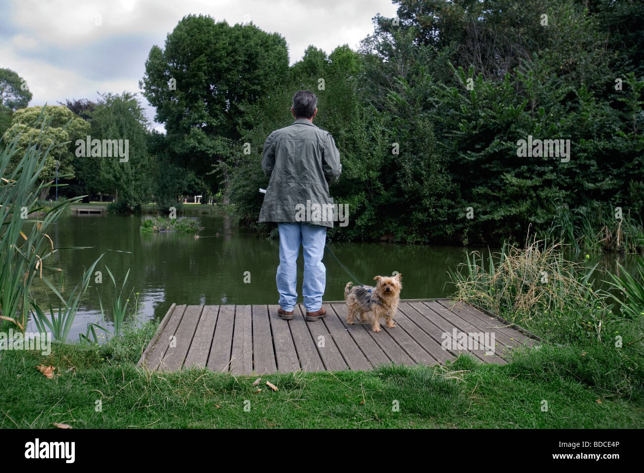 Un uomo con il suo cane sul lato del lago per la pesca sportiva nel Parco Victoria nella zona est di Londra Foto Stock