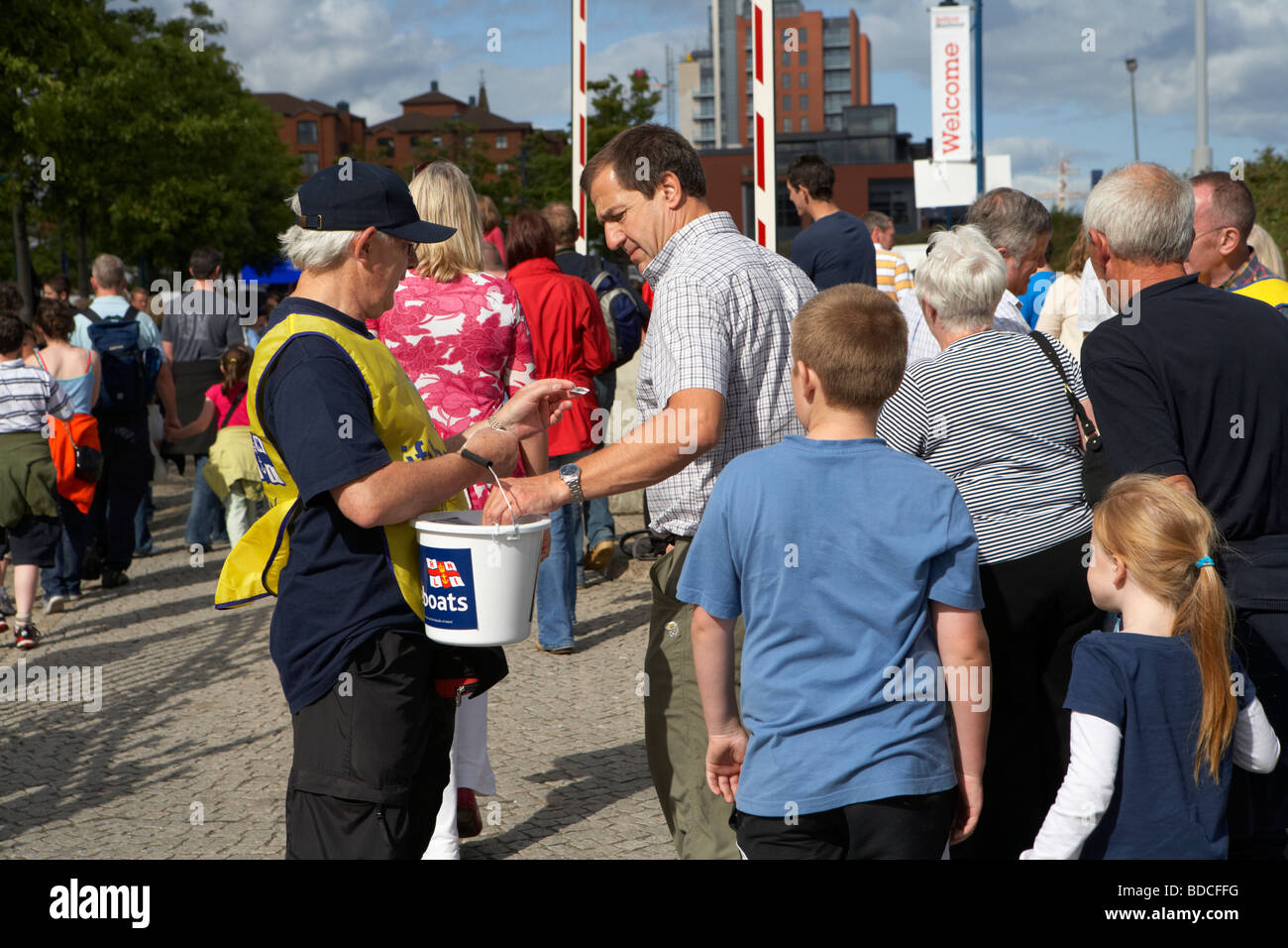 Volunteer facendo una carità la benna di raccolta per il RNLI in un affollato evento outdoor a Belfast Irlanda del Nord Regno Unito Foto Stock