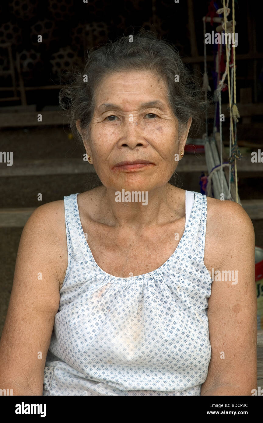 Donna seduta davanti a casa sua a Sukhotai, Thailandia Foto Stock