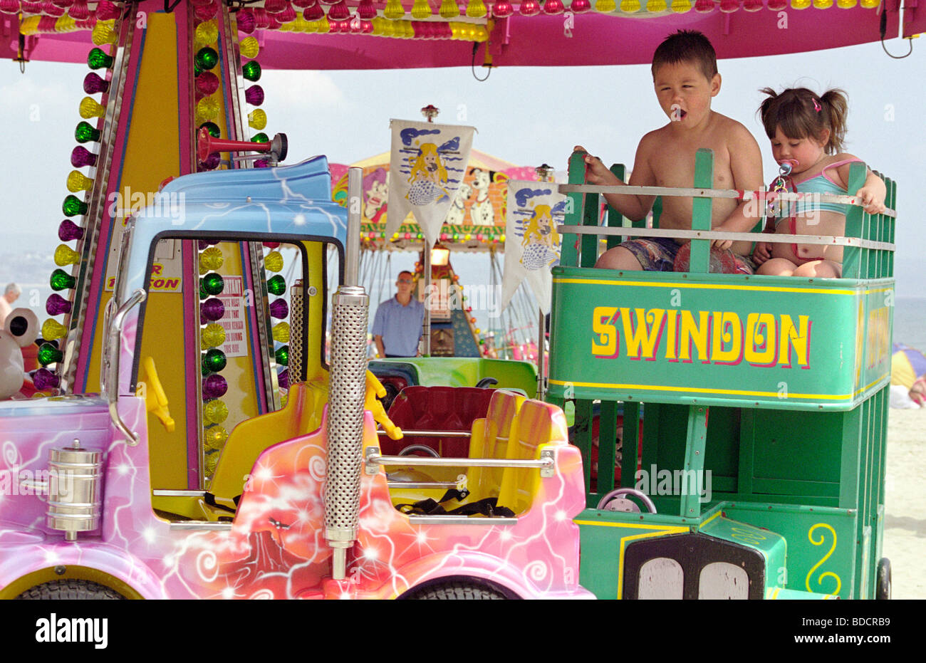 Due bambini di divertirsi su una rotonda sul mare di Weymouth Foto Stock