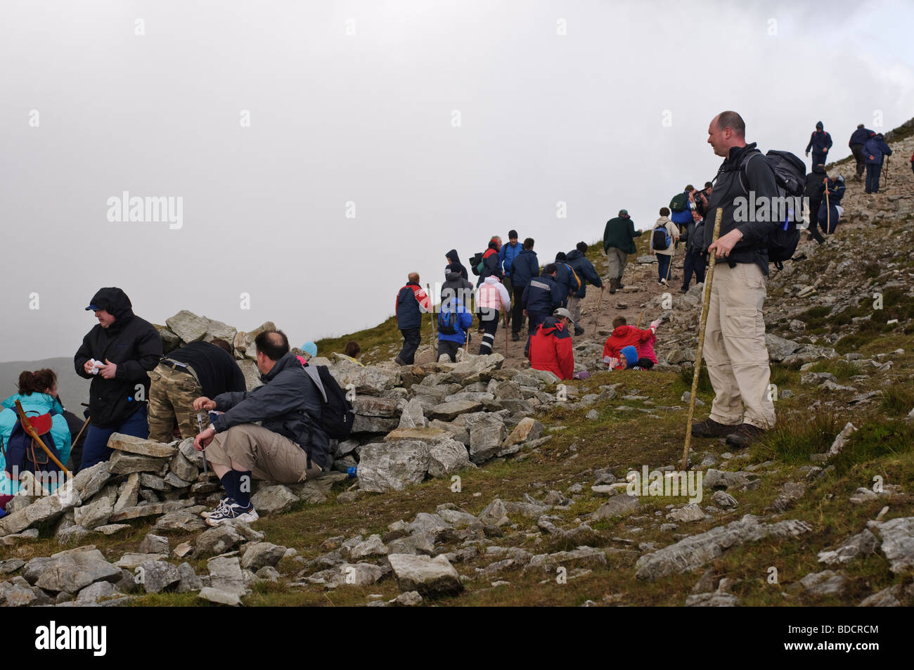 Pellegrino con bastone arrampicata si ferma a guardare la folla, Croagh Patrick su Reek, Domenica, 25 Luglio 2009 Foto Stock