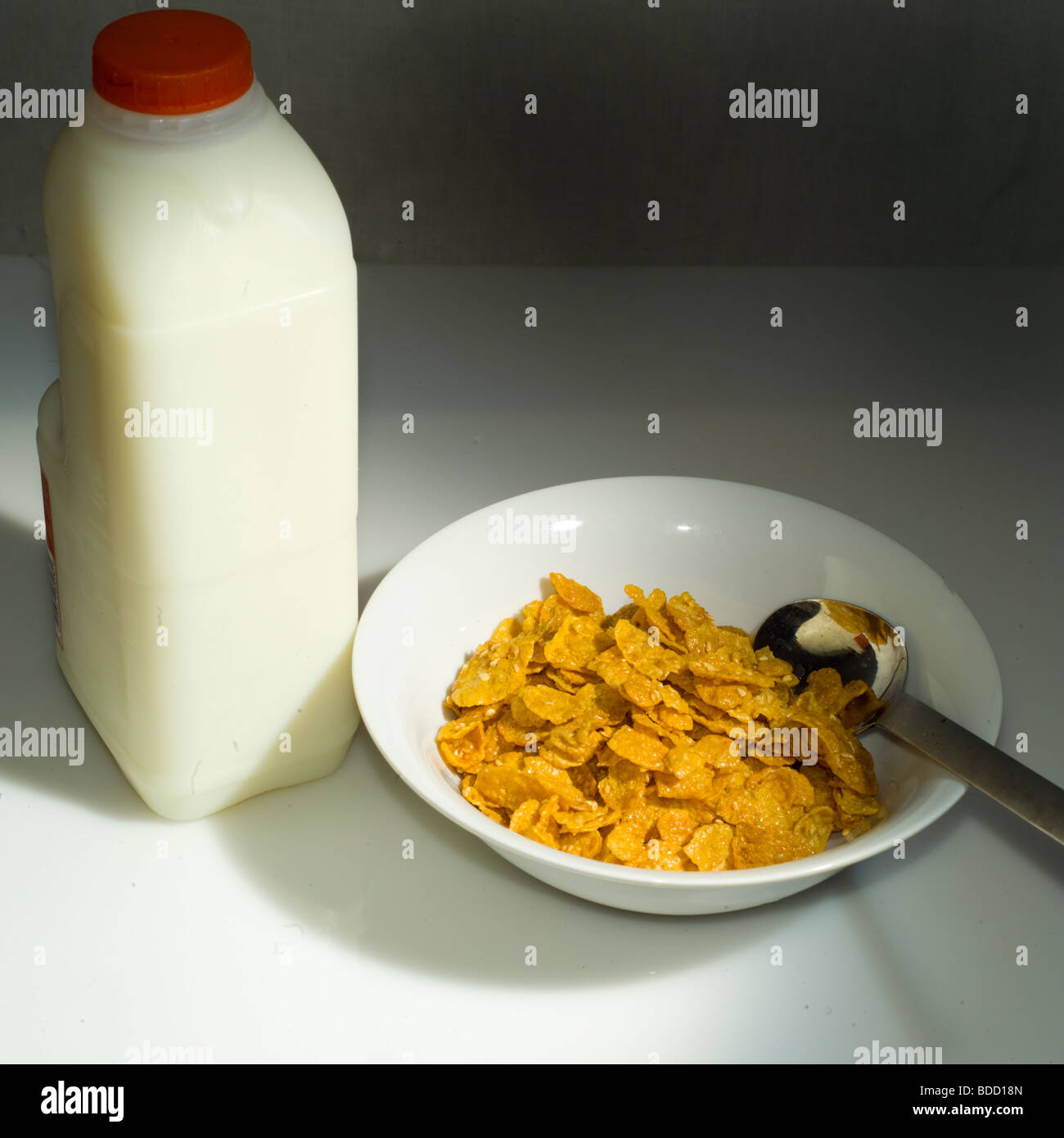 Cereali per la prima colazione e una bottiglia di latte su un tavolo bianco Foto Stock