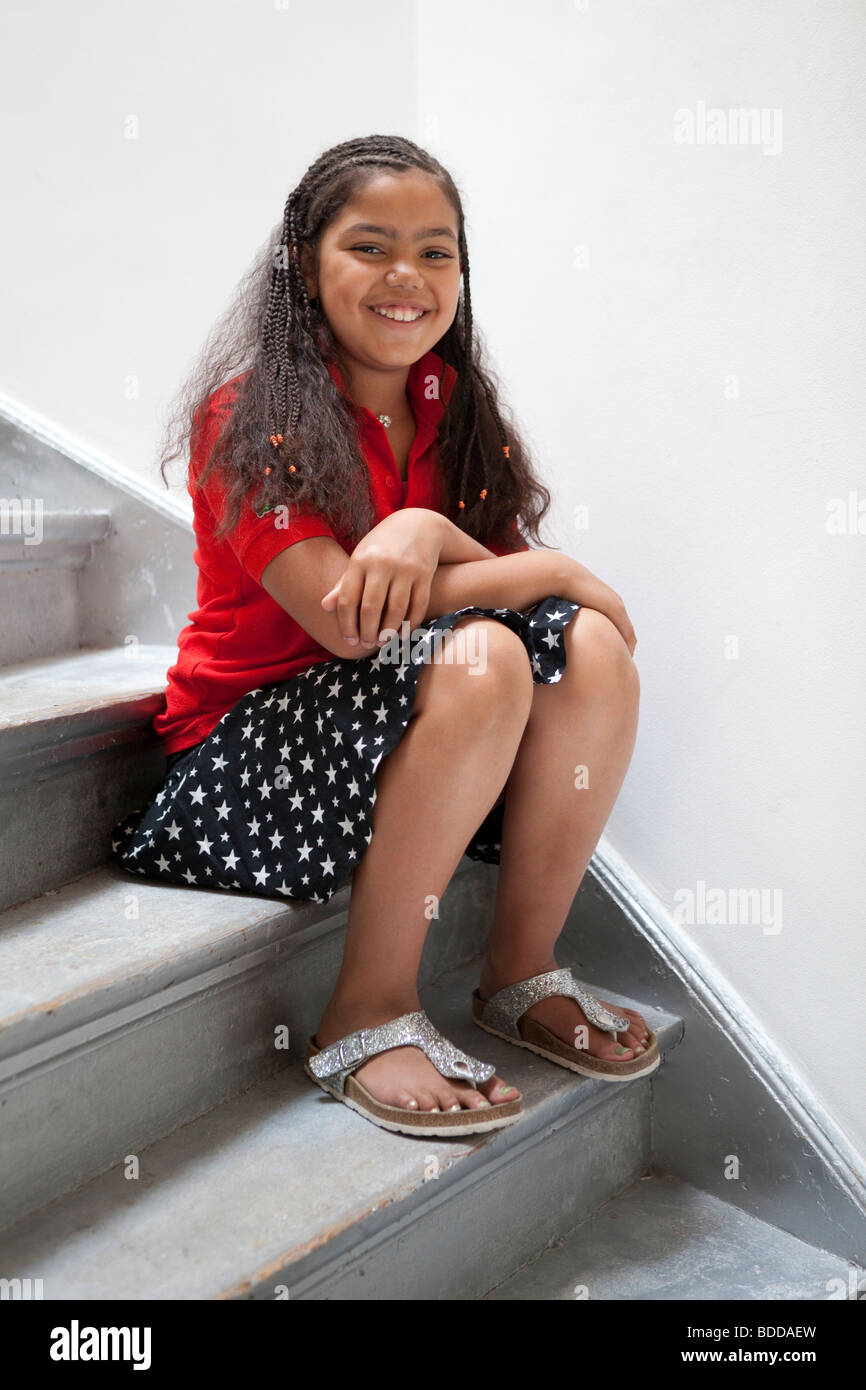 Piccolo felice ragazza seduta sulle scale Foto Stock