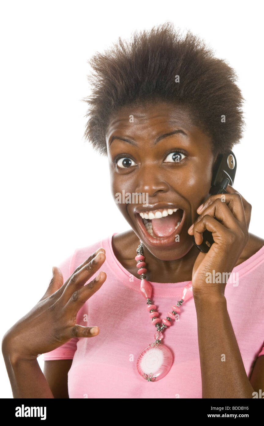 Ritratto in studio di un attraente donna africana su un telefono cellulare felice ed emozionato contro un bianco puro (255) dello sfondo. Foto Stock