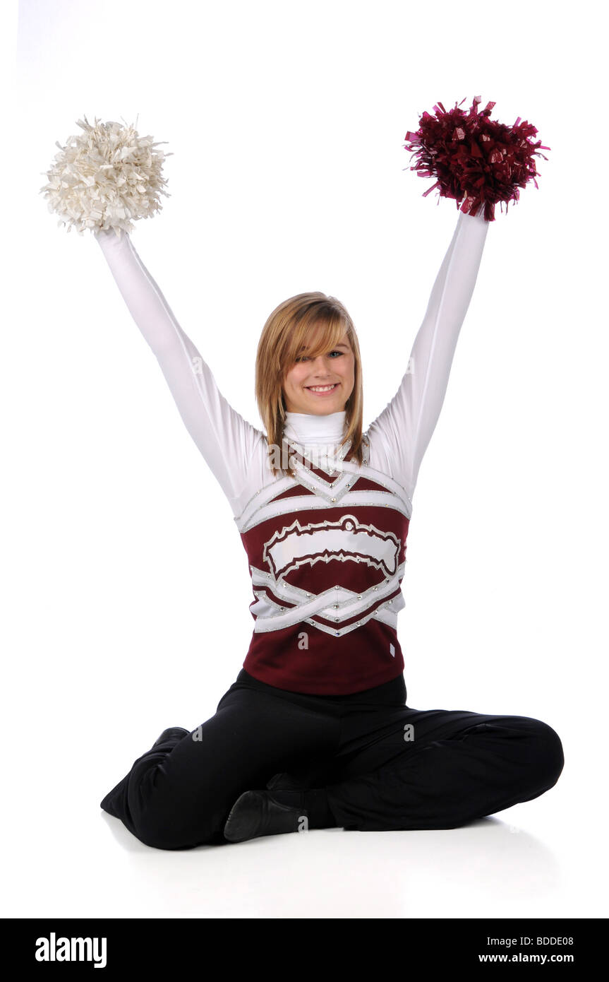 Teen cheerleader con il pom-pom seduto su uno sfondo bianco Foto Stock