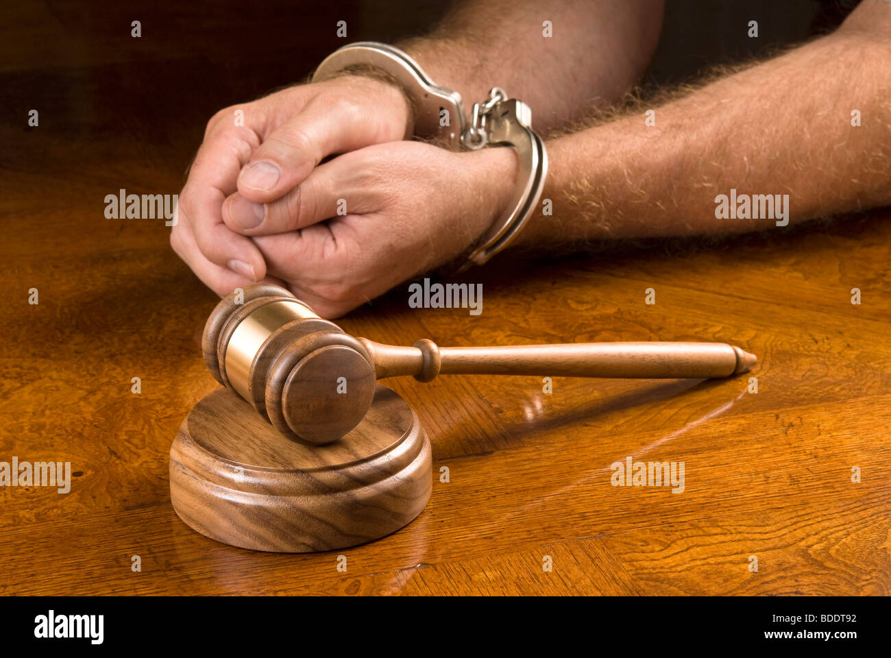 Un uomo arrestato attende il giudice di utilizzare il suo martello per eseguire il rendering di una decisione. Foto Stock