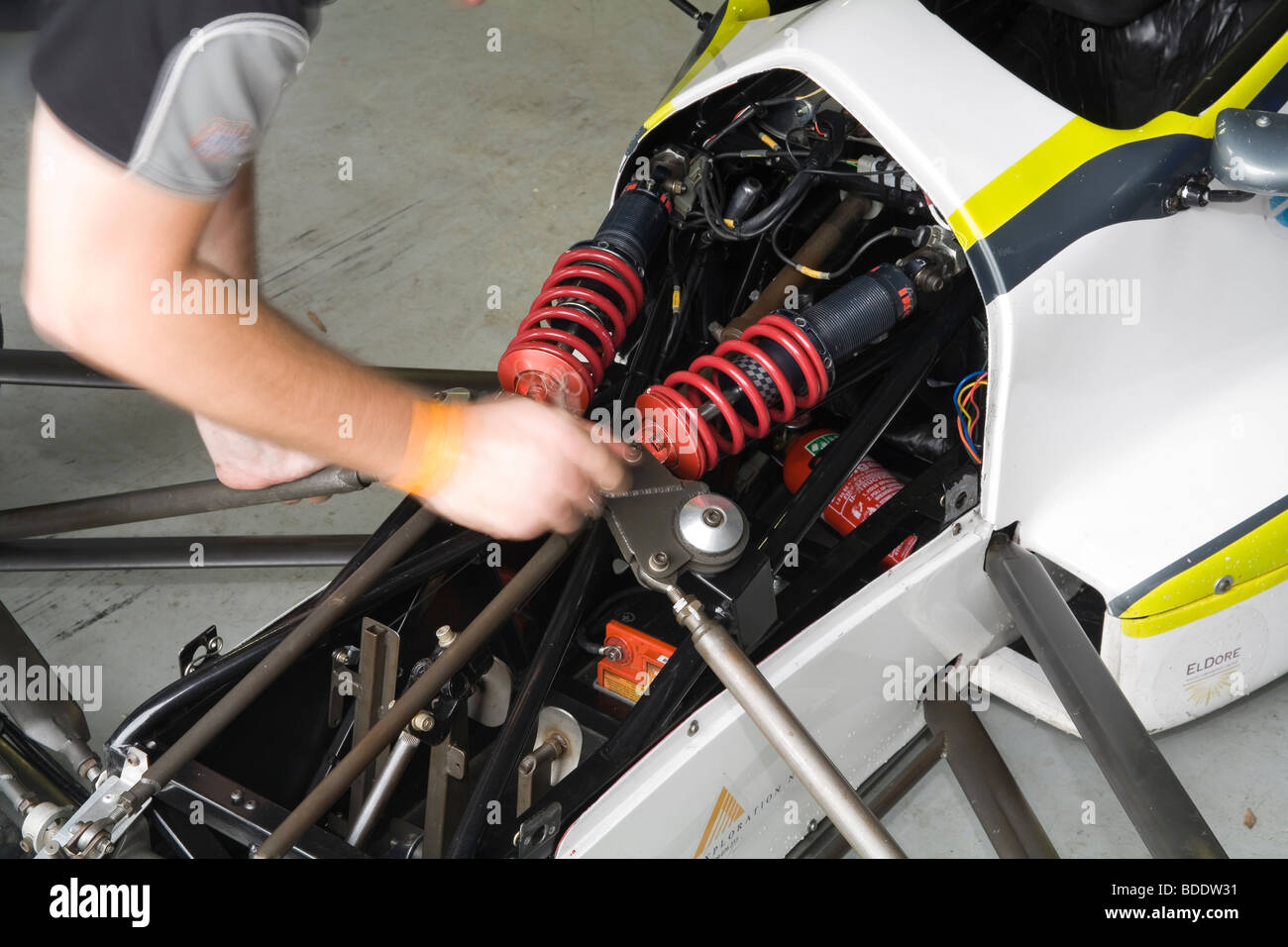 Le mani del meccanico lavorando su ammortizzatore setup su un aperto ruote vettura da gara. Foto Stock