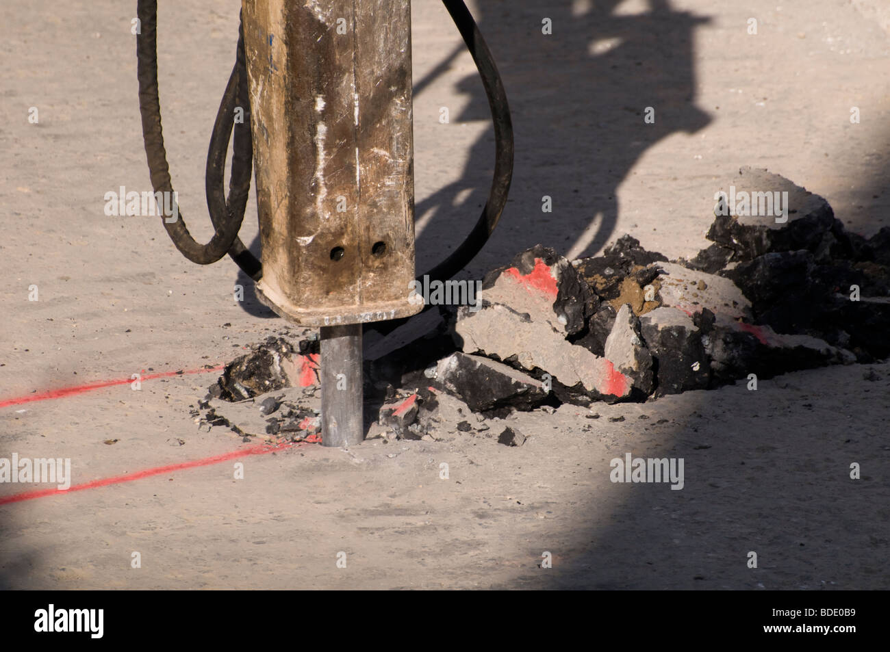 Una macchina di scavare attraverso una strada asfaltata della superficie Foto Stock