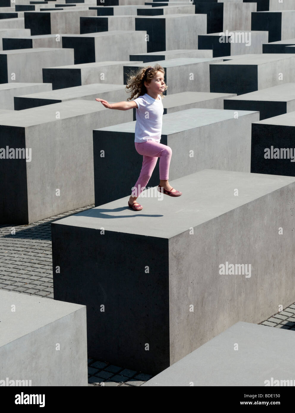 Giovane ragazza in posa sulla parte superiore dei blocchi in calcestruzzo presso il memoriale della assassinato ebrei di Europa nel centro di Berlino Germania Foto Stock