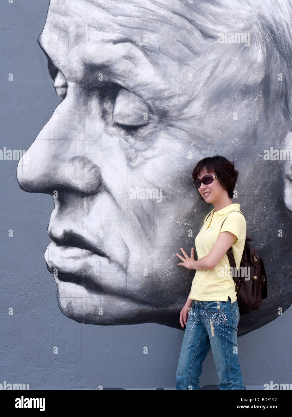 Turisti cinesi pone accanto appena ridipinto murale di Andrei Sacharov di Dmitry Vrubel sul muro di Berlino a East Side Gallery Foto Stock